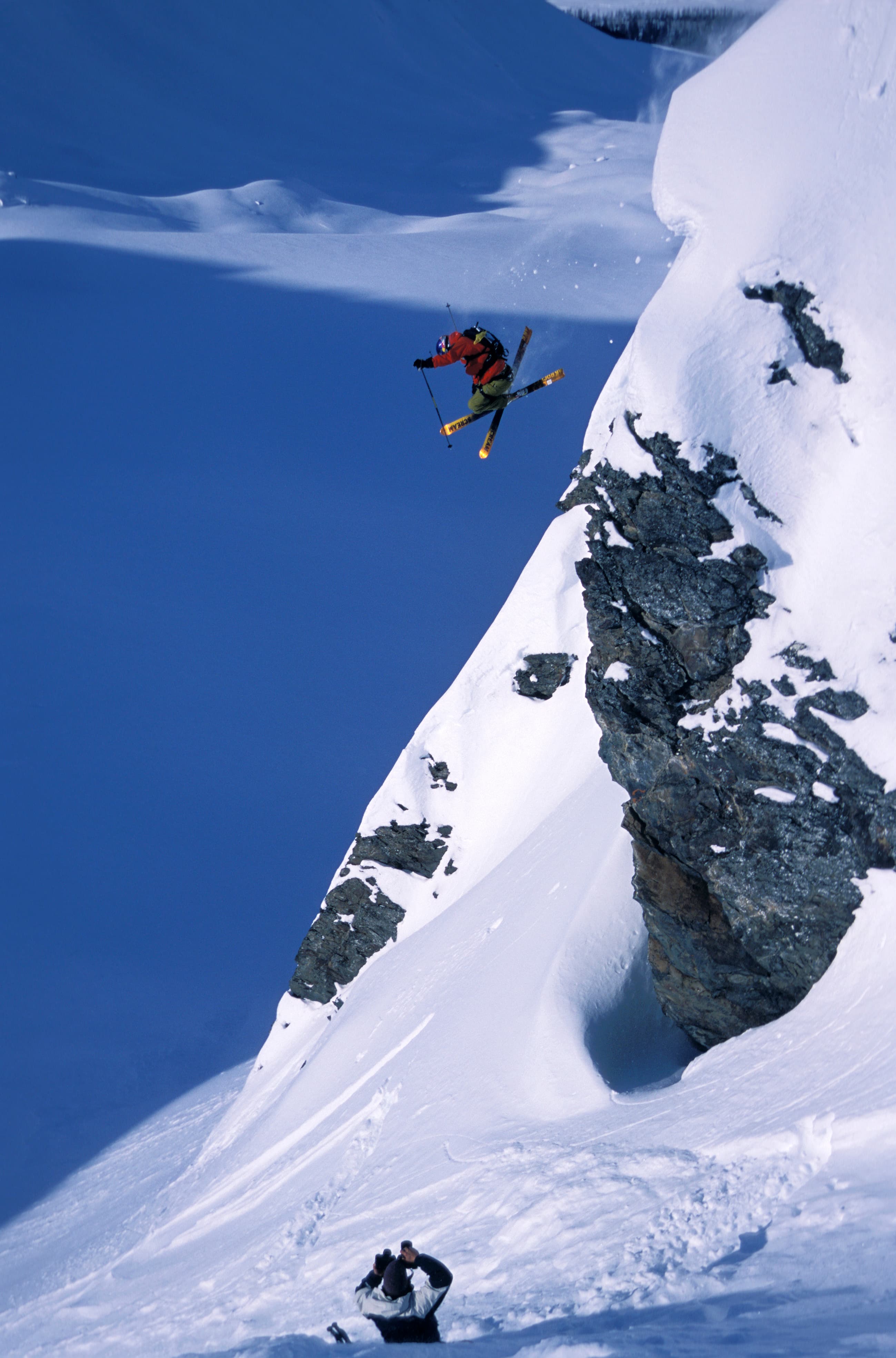 Chris Davenport launching a cliff in orange jacket