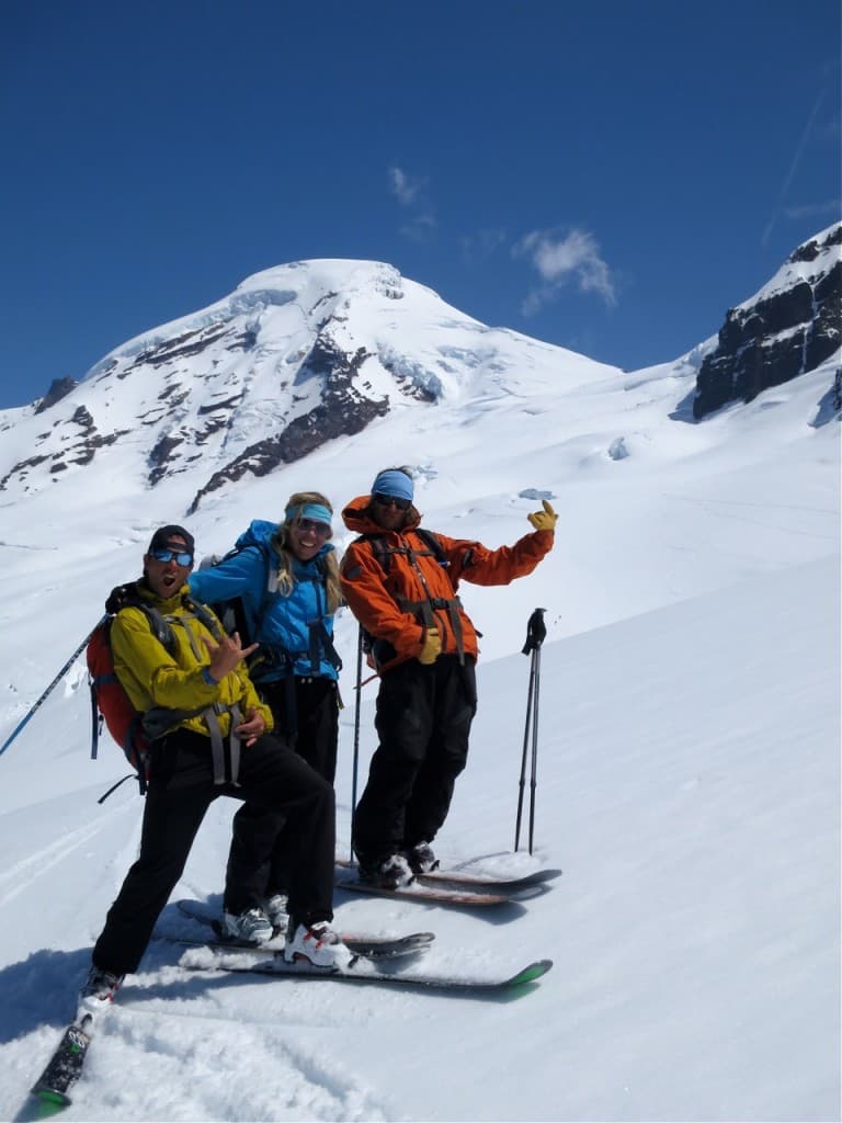 Three skiers on a glacier with a mountain peak