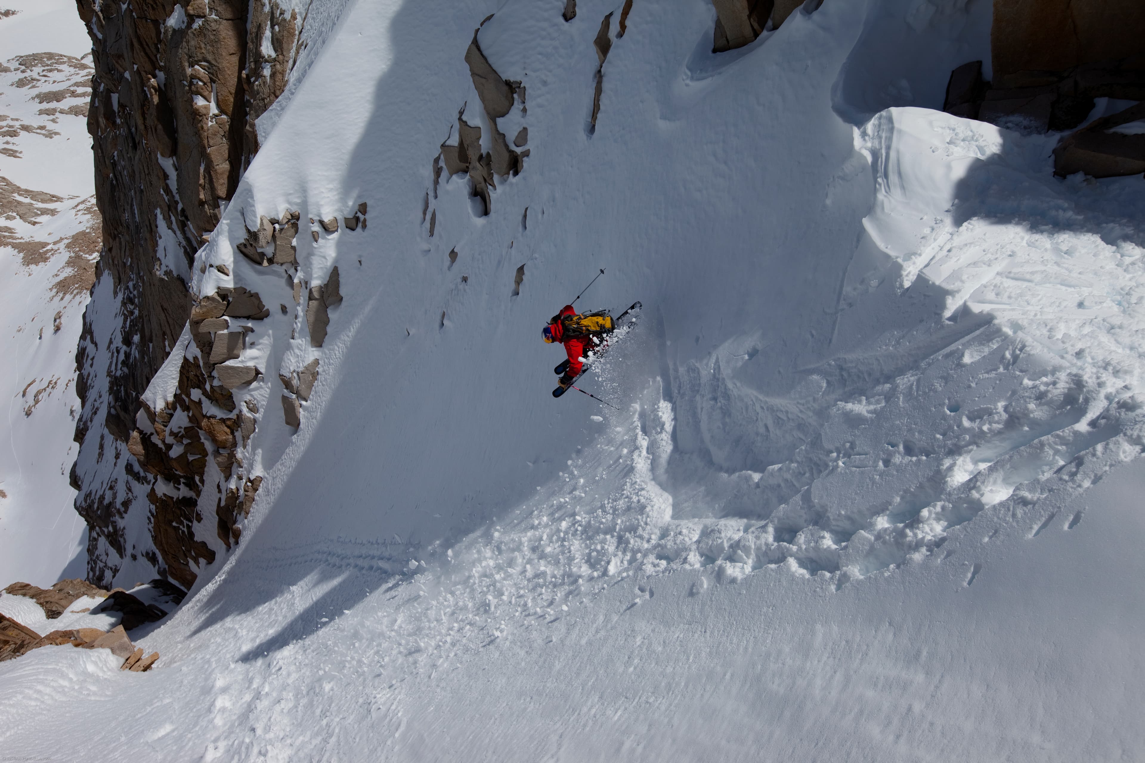 Chris Davenport skiing an extreme couloir in red jacket